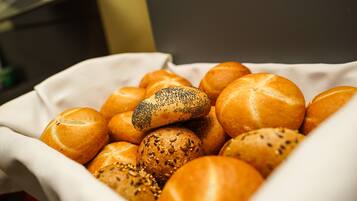 A basket filled with various types of bread rolls, including some with seeds and poppy seeds.