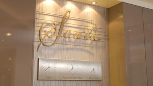 A wall clock with the word "Scelta" and three city names: Tokyo, Frankfurt am Main, and New York.
