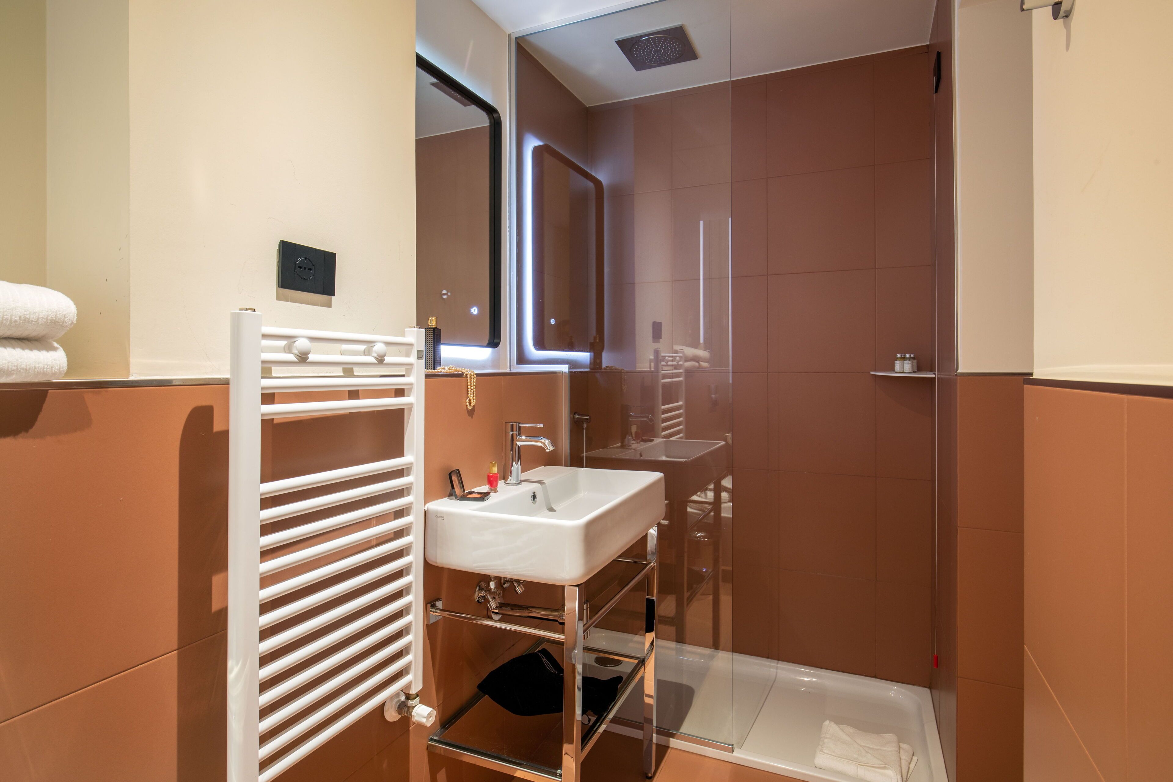 A modern bathroom with a white sink, mirror, and glass shower enclosure.