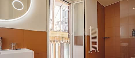 Un baño moderno con un espejo grande, un lavamanos y una zona de ducha.