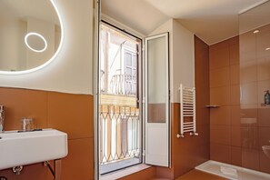 A modern bathroom with a large mirror, a sink, and a shower area. - 9Hotel Cesari (Rome)