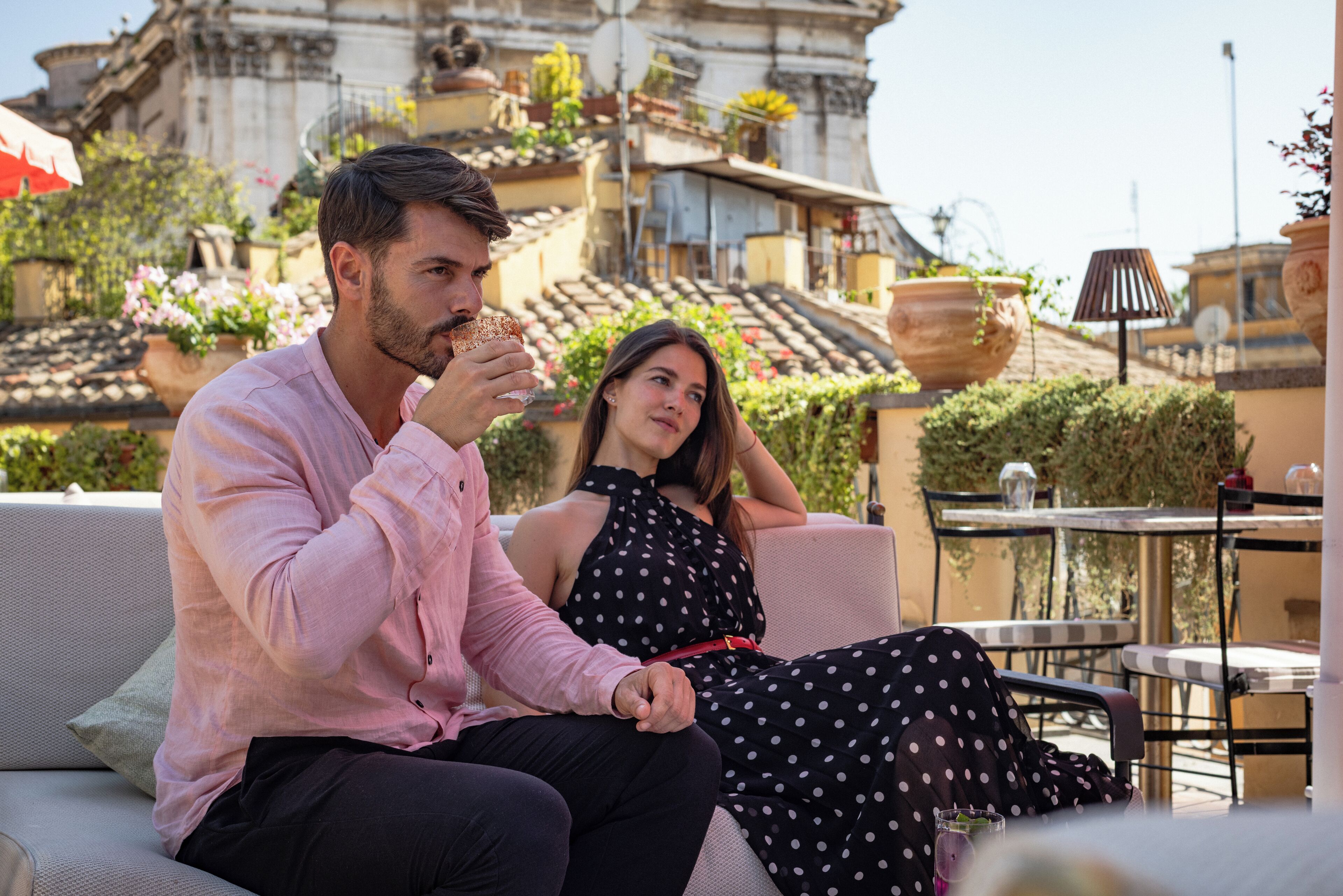 A couple sitting on a sofa with a cityscape in the background.