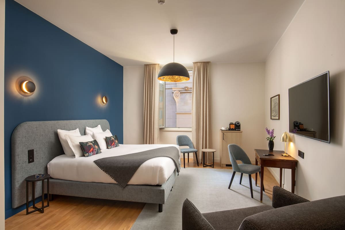 Une chambre d’hôtel moderne équipée d’un grand lit, d’un bureau, d’une chaise et d’un téléviseur.