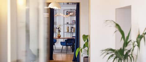 A modern interior with a dining area, a bookshelf, and a potted plant.