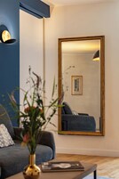 Una sala de estar moderna con un espejo grande, un sofá, una mesa de centro y un jarrón con flores.
