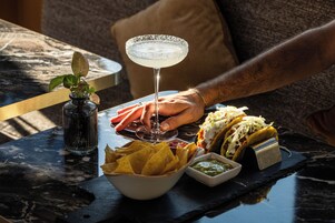 A table with a margarita glass, nachos, tacos, and a small bowl of salsa.