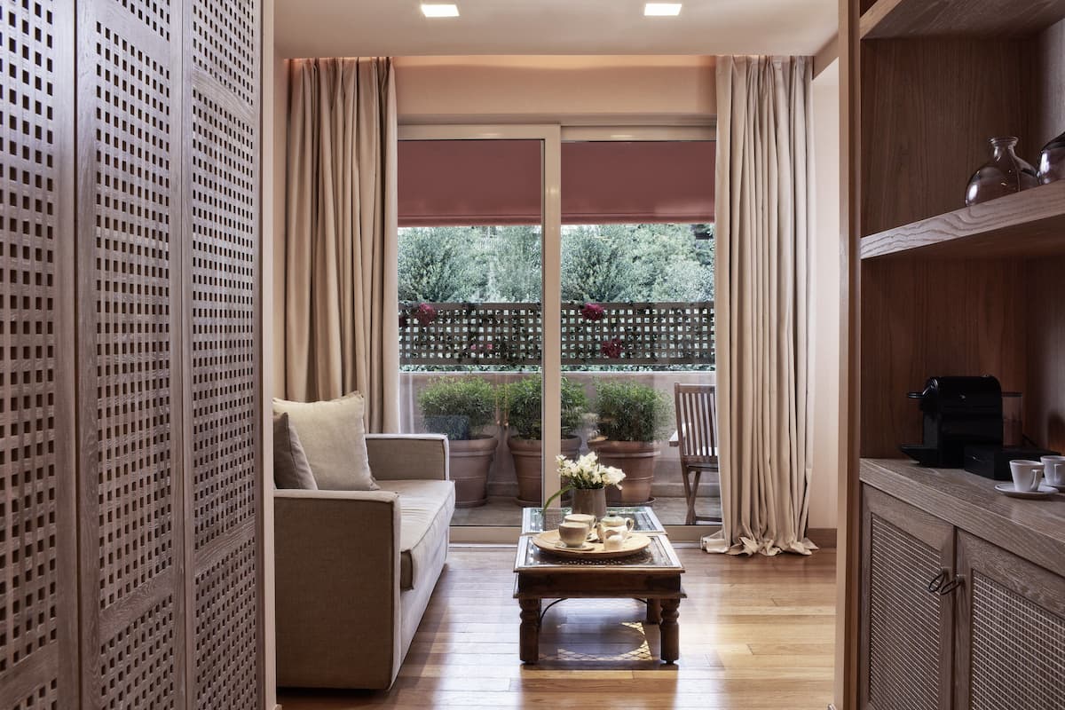 A cozy living area with a sofa, a coffee table, and a view of a balcony with potted plants.