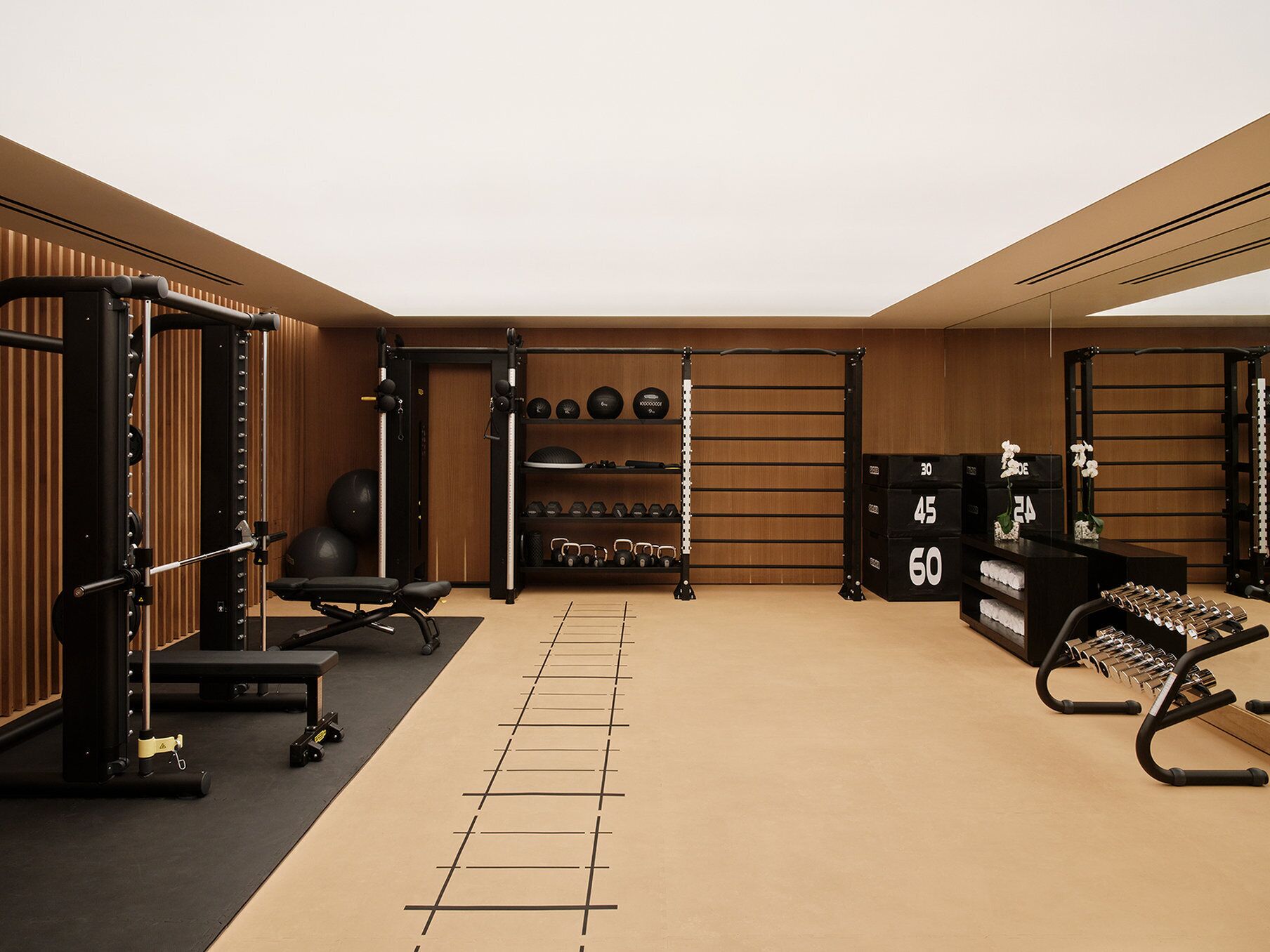 Een sportschool met gewichthefapparatuur, een bank en een rek met halters.