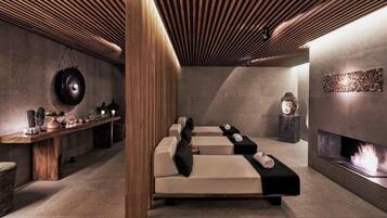Un spa moderno con techo de madera, una camilla de masaje, una chimenea empotrada y una estatua decorativa de Buda.