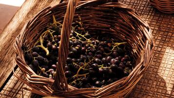 A wooden table with baskets containing grapes, tomatoes, and eggplants.