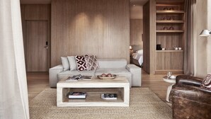 A modern living room with a sofa, coffee table, and a wooden cabinet with shelves. - The Margi (Vari-Voula-Vouliagmeni)