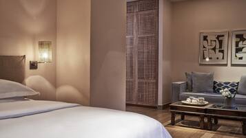Quarto de hotel com cama, sofá, mesa de centro e obras de arte nas paredes.