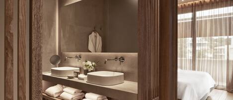 A modern bathroom with two sinks, a large mirror, and a vanity with neatly folded towels.