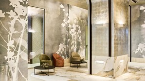 A modern lobby with marble flooring, two armchairs, a coffee table, and a large wall mural. - VP SOGNIO Madroño (Madrid)