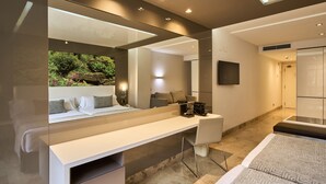 A modern hotel room with a large mirror, a desk, a bed, and a view of a landscaped garden. - VP SOGNIO Madroño (Madrid)