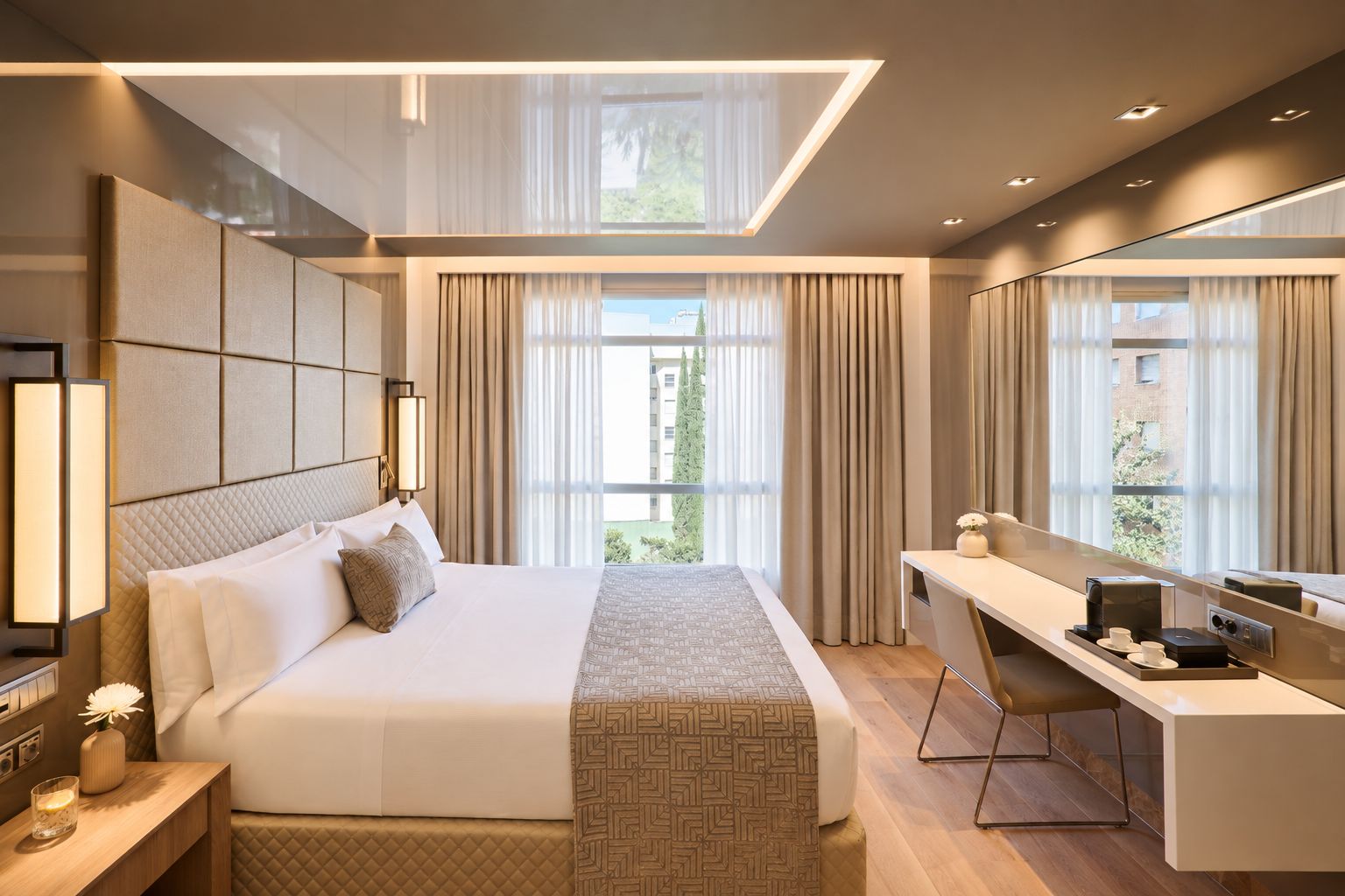 Une chambre d’hôtel moderne avec un grand lit, un bureau et une grande fenêtre avec des rideaux.