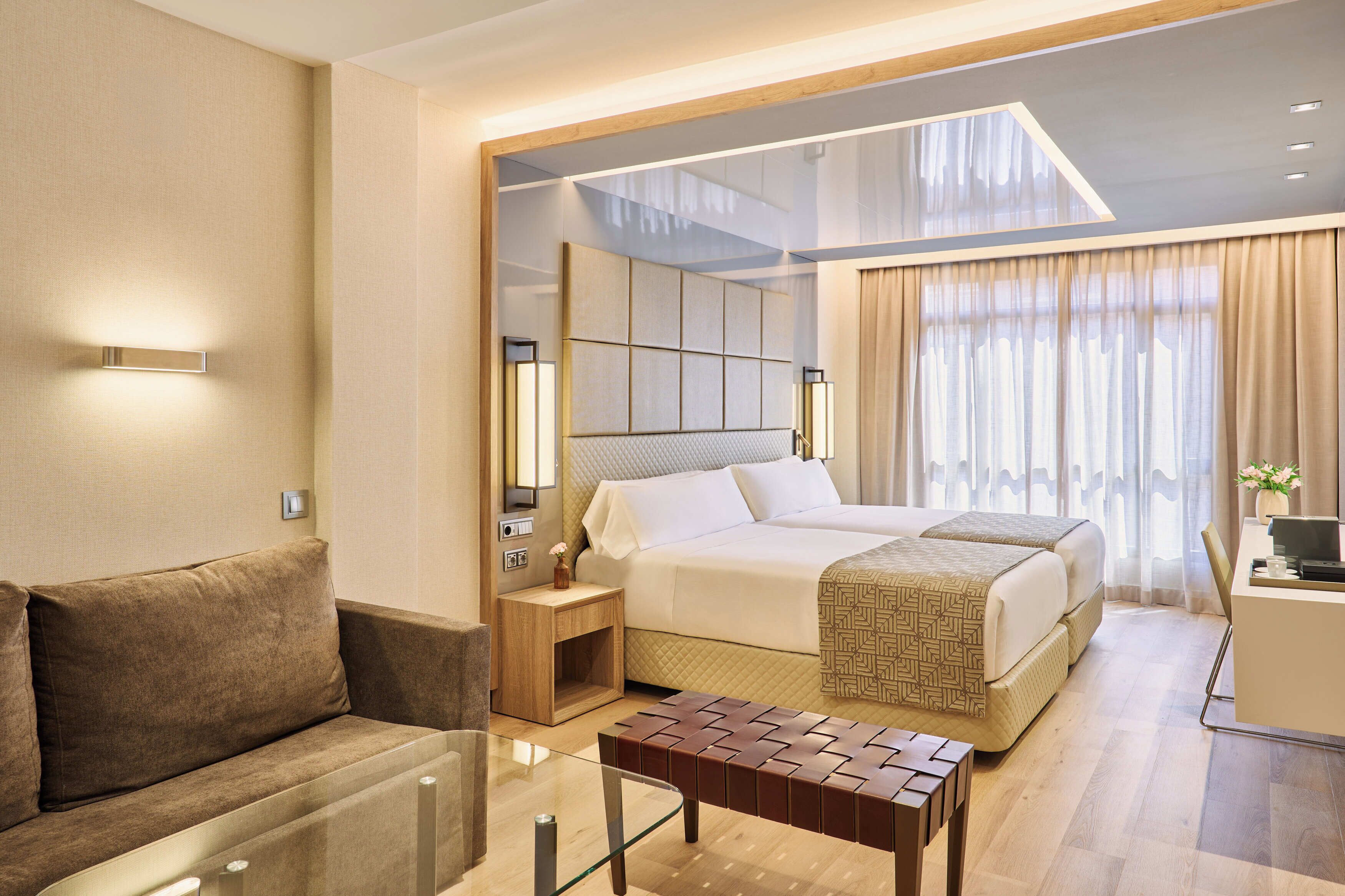 Habitación de hotel con cama, sofá, una mesita y un escritorio con silla.