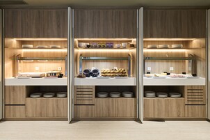 Una cocina moderna con armarios de madera, encimeras blancas y estantes empotrados para platos y utensilios.