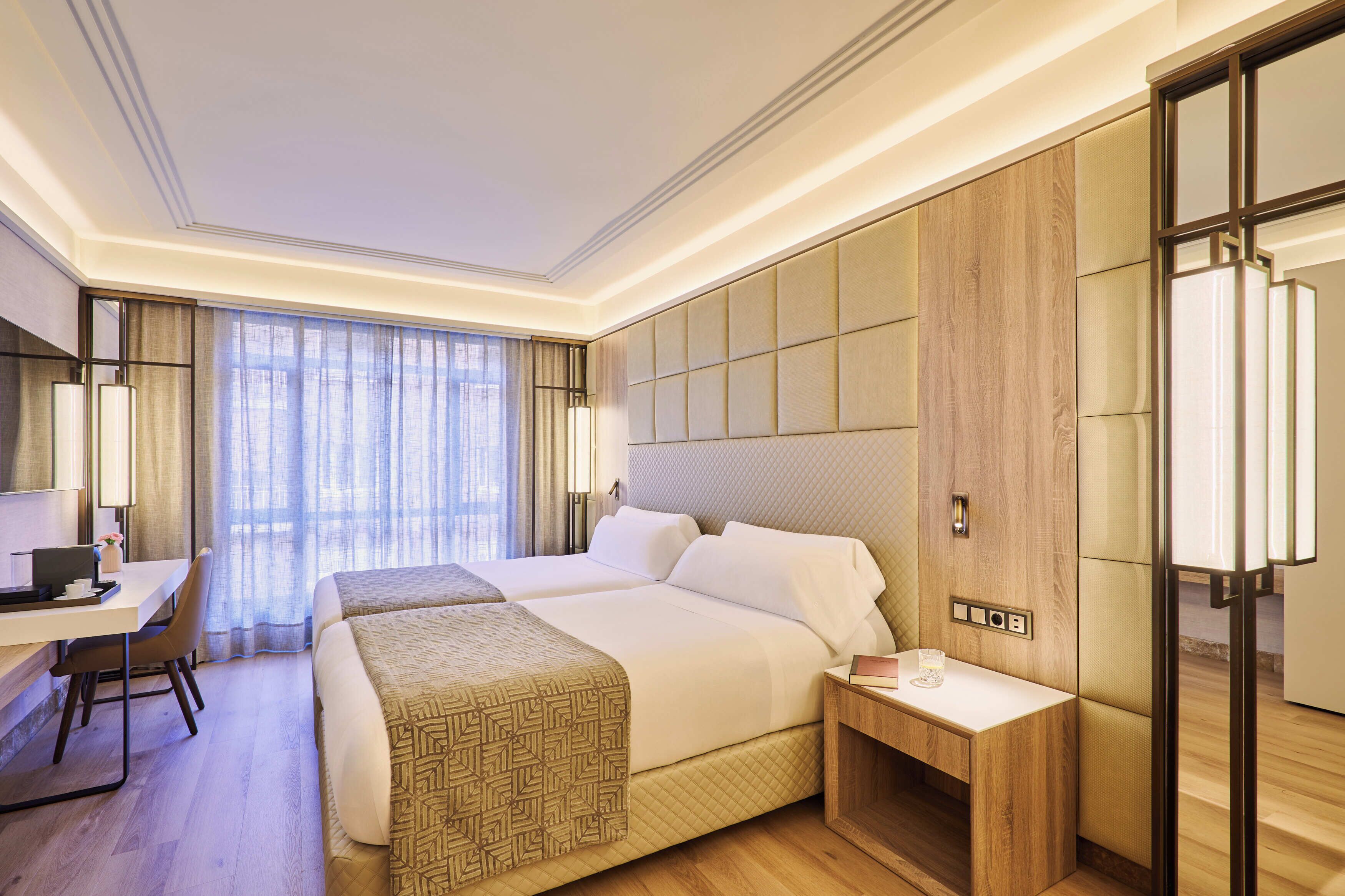 Habitación de hotel con una cama grande, mesitas de noche, un escritorio y una silla.