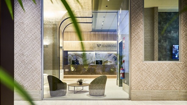 A modern interior with a reception desk, two seating areas, and a patterned wall. - VP SOGNIO Madroño (Madrid)