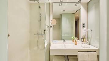 Un baño moderno con ducha envuelta en vidrio, tocador con espejo y perchero.