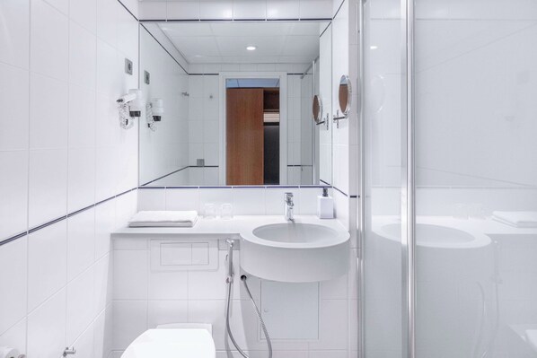 A modern bathroom with a glass shower enclosure, a white sink, and a mirror above the sink.