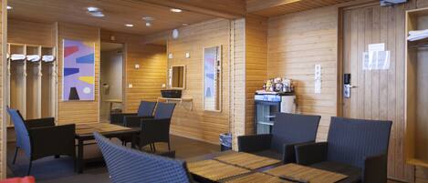 A wooden interior with seating arrangements and a small kitchenette area.