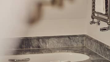 Un baño con lavamanos de mármol, una toalla colgada en la pared y ducha con vapor.