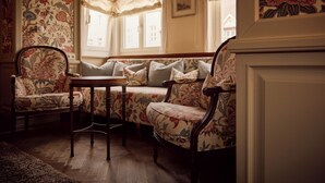 Une pièce comprenant un canapé à motifs floraux, une chaise en bois et une petite table.