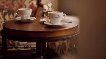 Una mesa de madera redonda con dos tazas y platillos blancos, uno con una cuchara, y un recipiente pequeño.