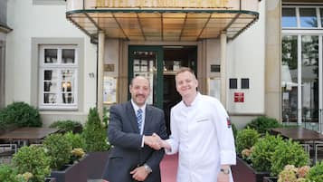 Een man en een vrouw schudden elkaar de hand voor Hotel Detmolder Hof.