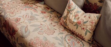 A sofa with floral upholstery and multiple cushions.