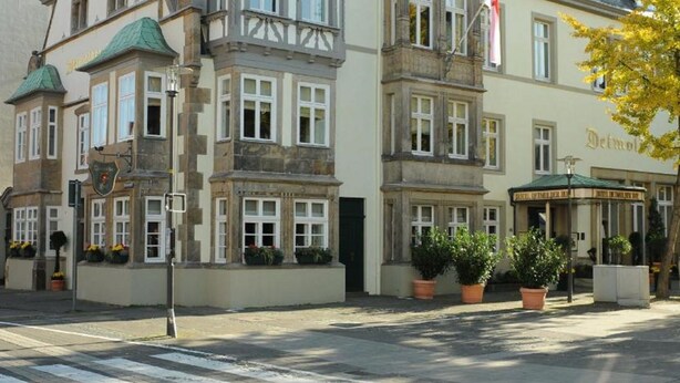 Un bâtiment historique doté d’une tour imposante, de nombreuses fenêtres et d’une enseigne indiquant la présence d’un restaurant.