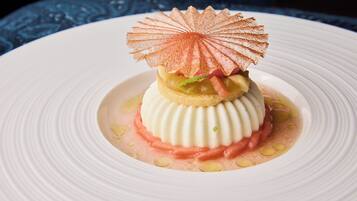 A dessert on a white plate with a decorative sugar shell on top.
