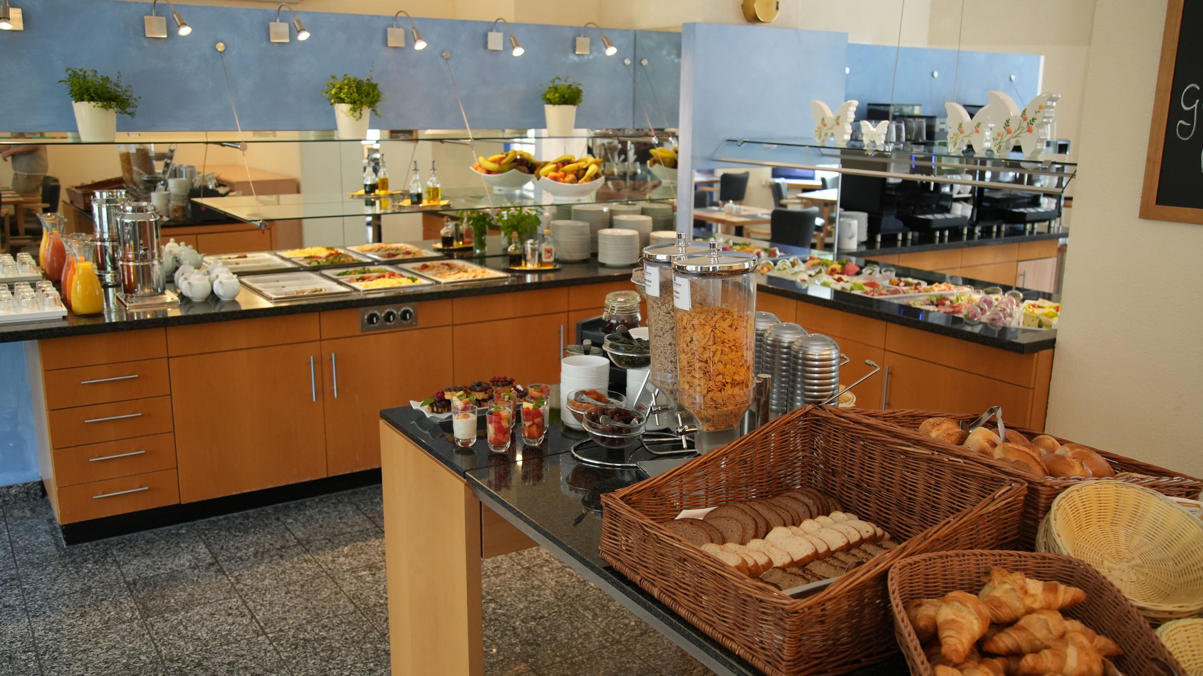 A buffet with various food items, including fruits, cereals, and pastries.