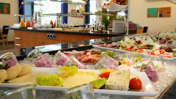 Buffet com diversos pratos frios e queijos sobre gelo.
