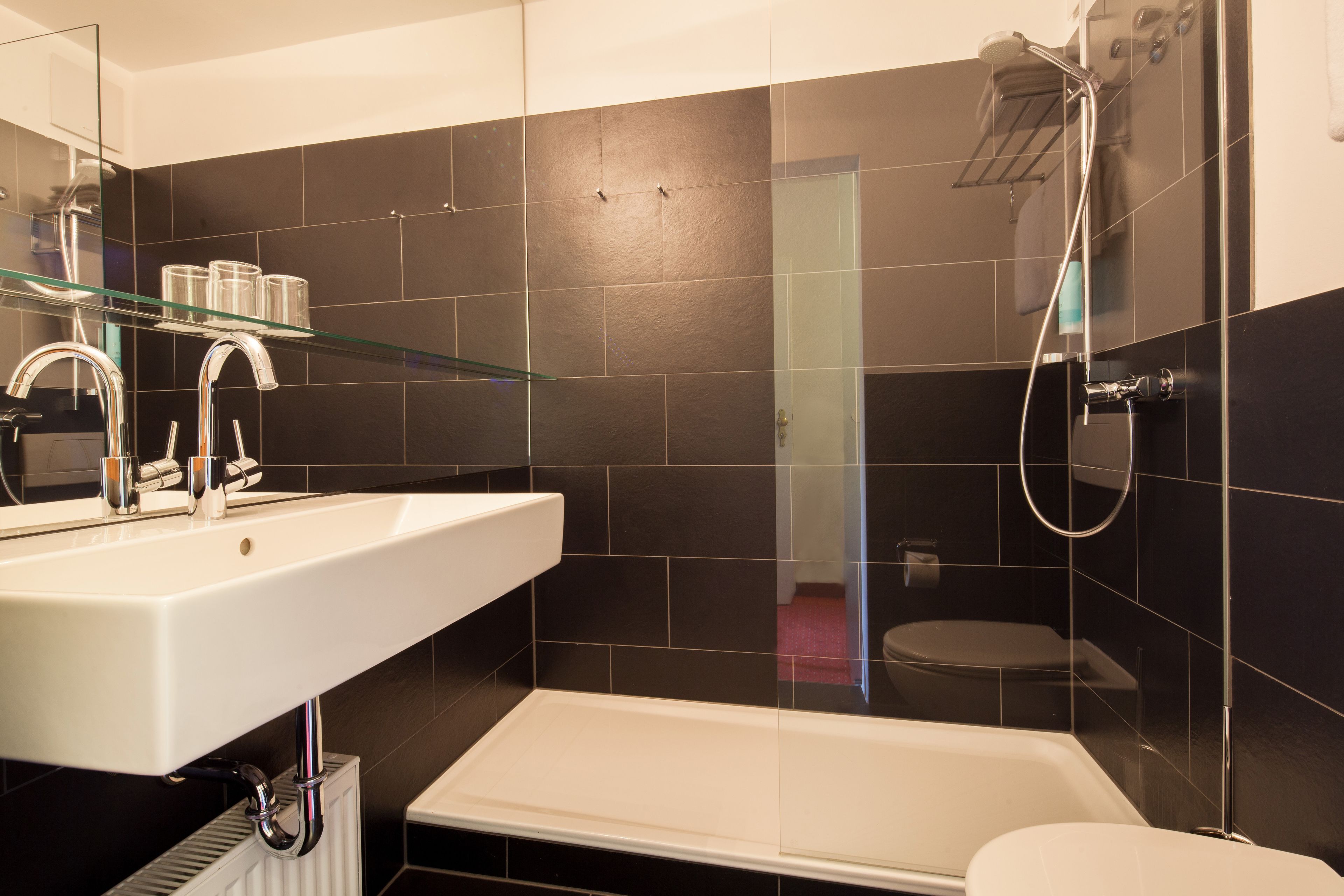 A modern bathroom with a white sink, a glass shelf, a bathtub, and a shower.