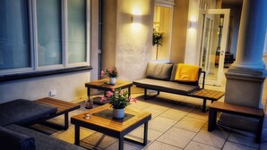 A modern lounge area with a sofa, two wooden tables, and a bench.