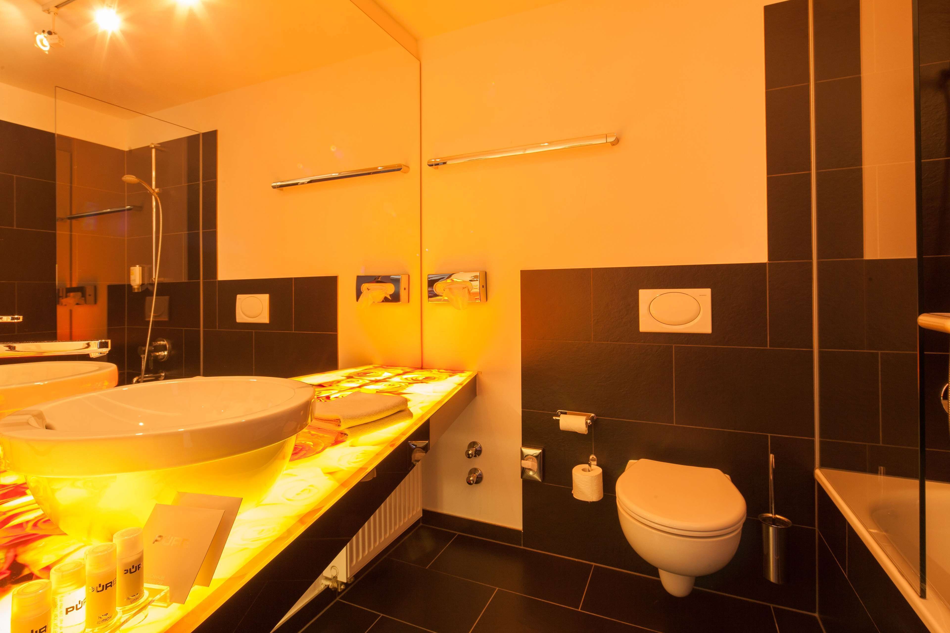A modern bathroom with a large sink, toilet, and bathtub.