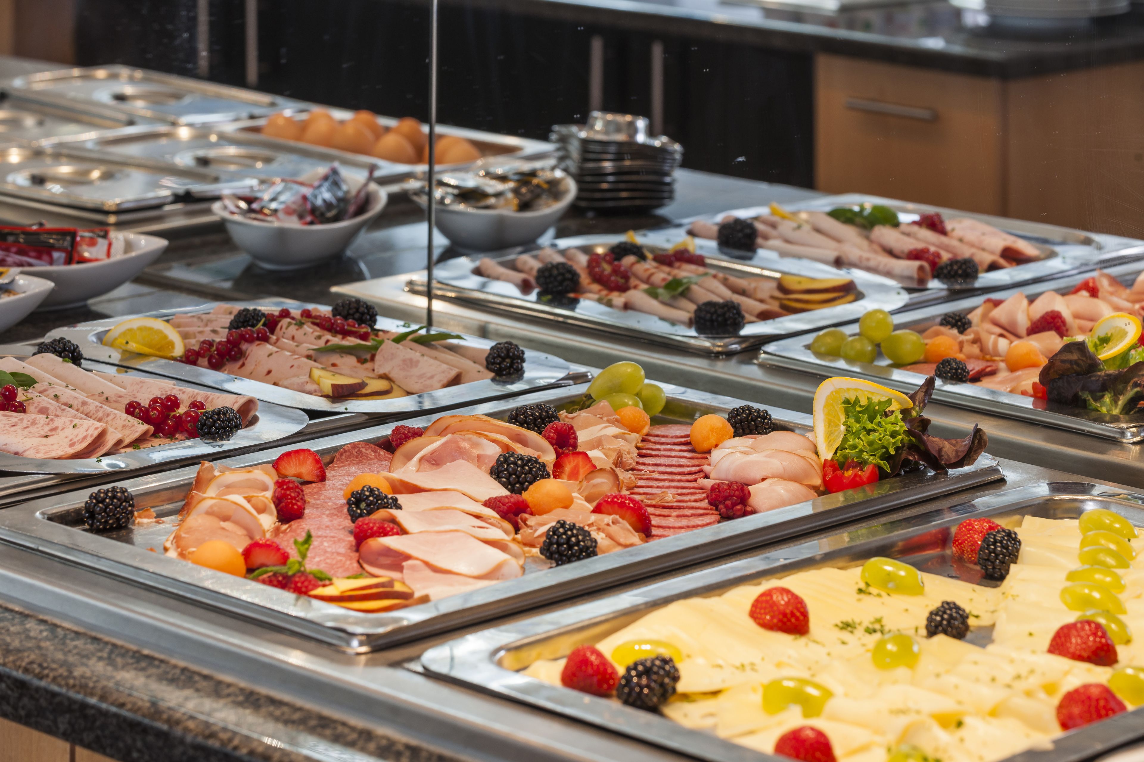 Een buffet met verschillende vleessoorten en fruit.