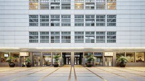 Un edificio moderno con una entrada amplia, plantas en macetas y piso de baldosas.