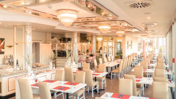 A spacious restaurant with long tables and chairs, a bar area, and a modern interior design. - Hotel Stuttgart Sindelfingen City by Tulip Inn (Sindelfingen)