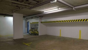 A parking garage with concrete floors, yellow parking lines, and a bicycle leaning against a wall. - Hotel Stuttgart Sindelfingen City by Tulip Inn (Sindelfingen)