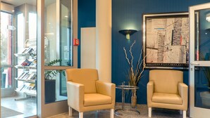 A reception area with two beige armchairs, a small round table, and a map on the wall. - Hotel Stuttgart Sindelfingen City by Tulip Inn (Sindelfingen)