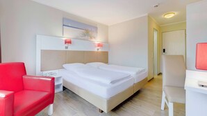 A hotel room with a bed, a red chair, a desk, and a painting on the wall. - Hotel Stuttgart Sindelfingen City by Tulip Inn (Sindelfingen)