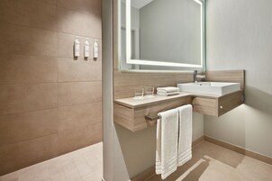 Un baño moderno con un espejo grande, un lavamanos y dos botellas de champú en la pared.