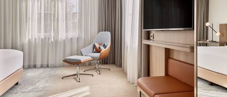 A hotel room with a bed, a desk, a chair, a TV, and a window with curtains.