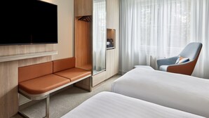 Una habitación de hotel moderna con televisor de pantalla plana, un sofá, una silla y una cama.
