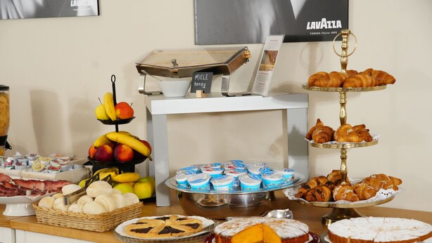 Una mesa de buffet con diversos alimentos, incluyendo pasteles, frutas y postres.