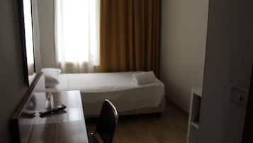 Una habitación de hotel con una cama, un escritorio con un control remoto y una silla.